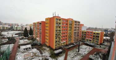 výhled na okolní panelové domy a dětské pískoviště
