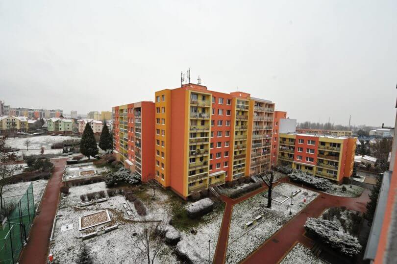 výhled na okolní panelové domy a dětské pískoviště