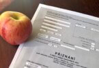 jablíčko na stole, vedle něho leží formulář "daňové přiznání k dani z nabytí nemovitých věcí"