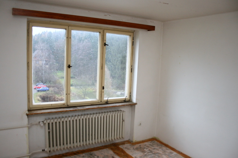 pokoj v původním stavu s oknem a topením