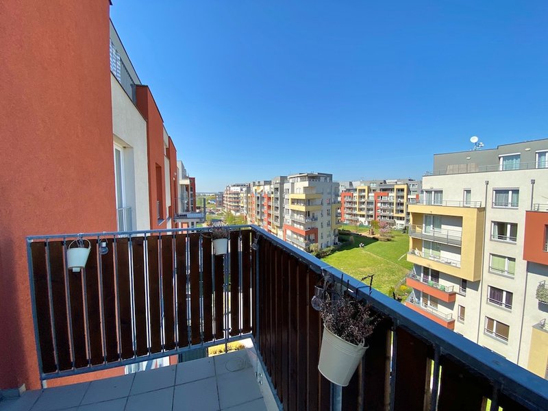 balkon, výhled na okolní bytové domy, modrá obloha