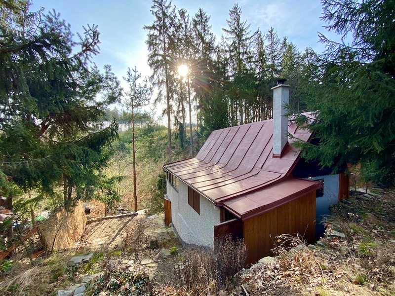 chata v lese, střecha, pohled na údolí a zapadající slunce