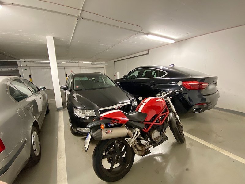 garážové stání, kde jsou zaparkována auta a motorka