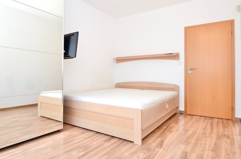 ložnice s manželskou postelí, dřevěné dveře, vestavěná skříň se zrdcadlem