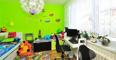 místnost se zelenou stěnou, židle, hračky, topení a lustr ve tvaru květiny