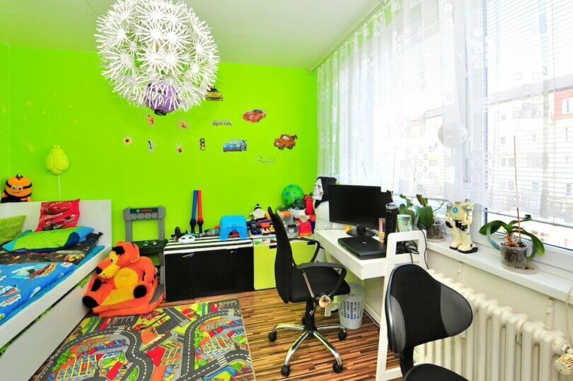 místnost se zelenou stěnou, židle, hračky, topení a lustr ve tvaru květiny